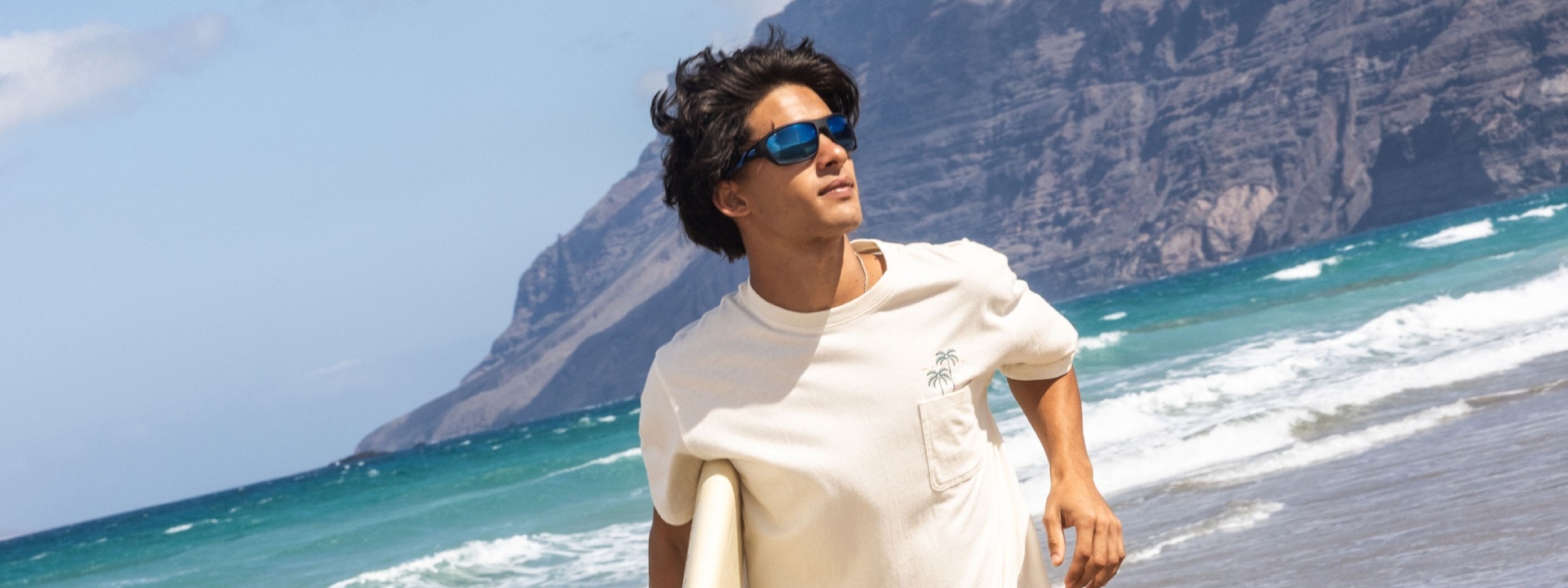 Mann mit Sonnenbrille läuft am Strand